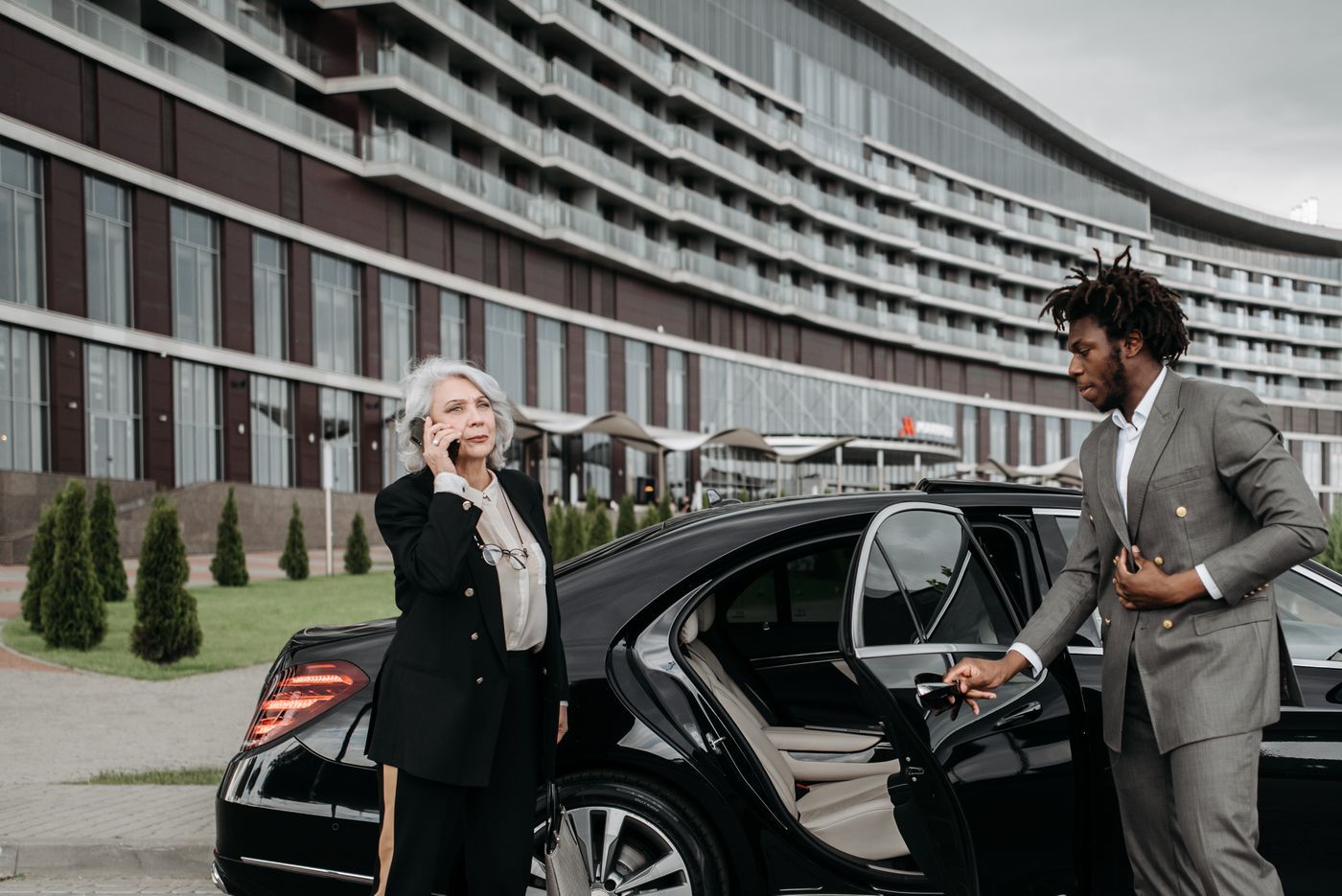 Executive sedan parked in a corporate basement with chauffeur opening the rear door